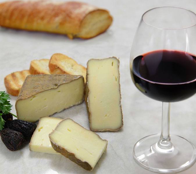 A close up view of a hard cheese and a glass of red wine, photo by Gourmet Food Store