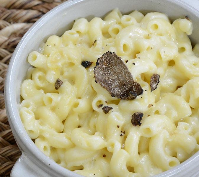 bowl of delicious mac and cheese pasta topped with black truffle slice