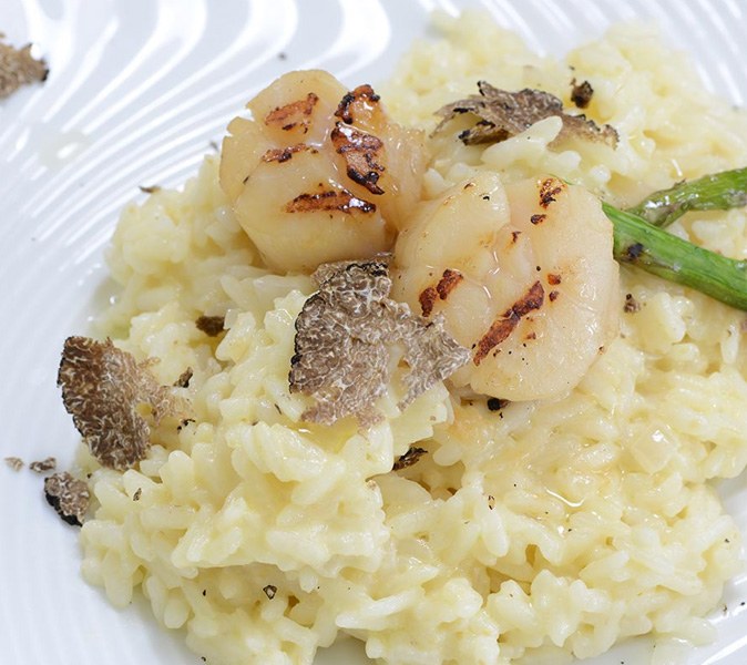 plate of delicious risotto with scallops, black truffles and asparragus